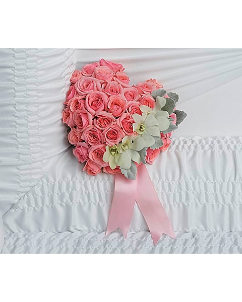 Heart-shaped casket insert with pink spray roses, white dendrobium orchids, dusty miller, and light pink ribbon.