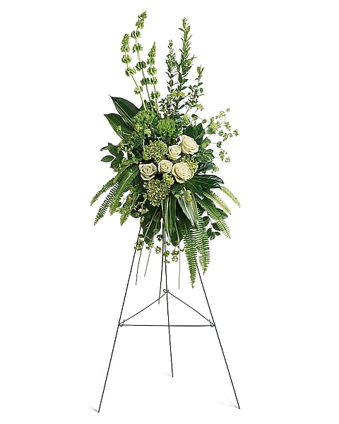Standing sympathy spray with white and green roses, green hydrangea, bells of Ireland, and lush foliage.