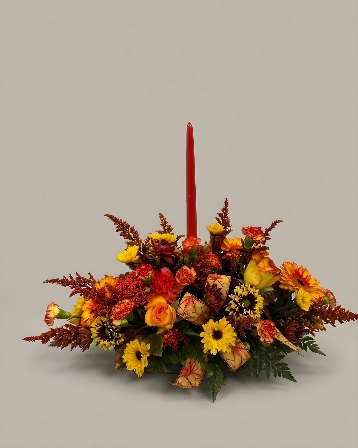 Low autumn centrepiece in rust and gold with a single orange taper candle