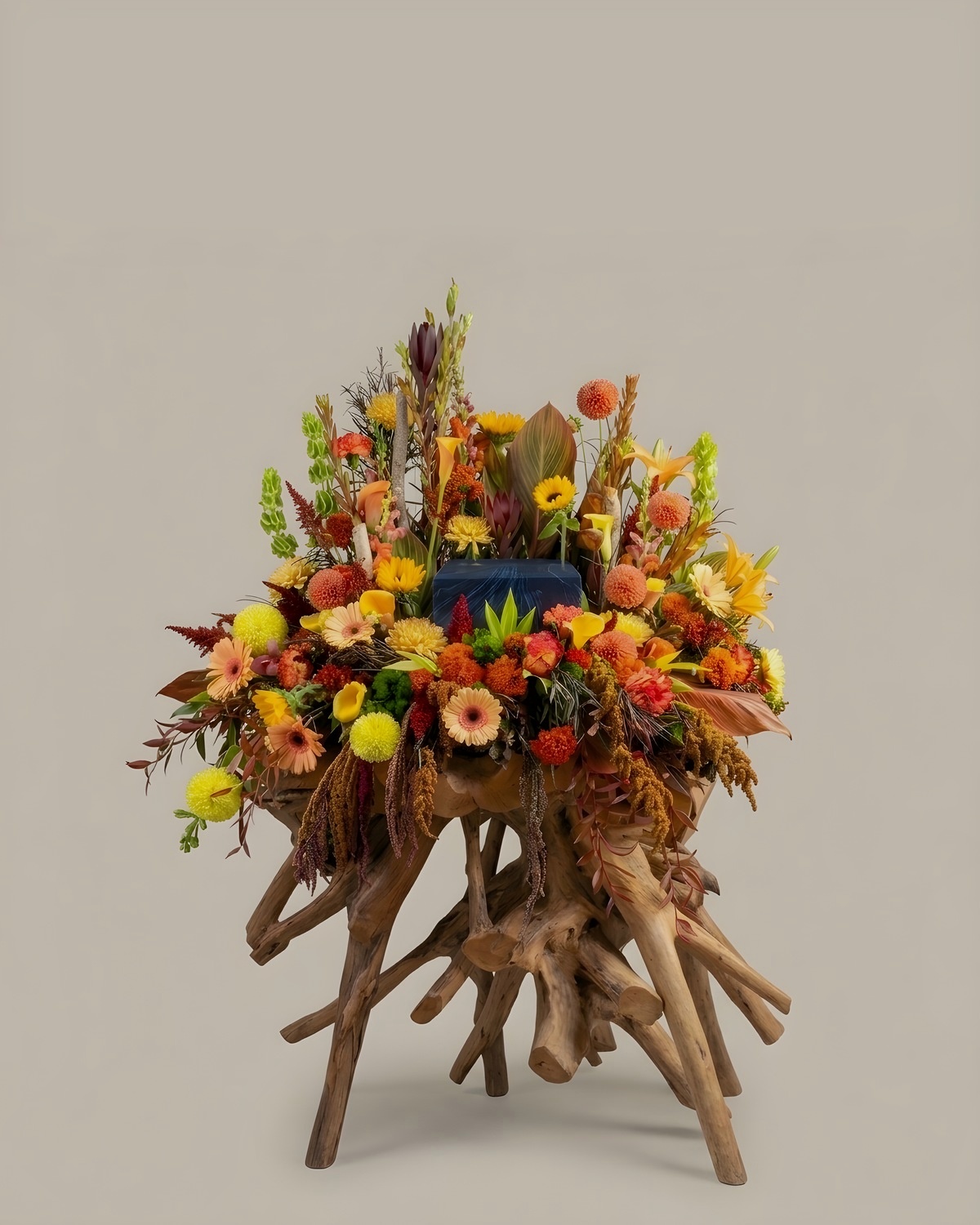 Urn tribute built into a driftwood root in orange, rust and gold
