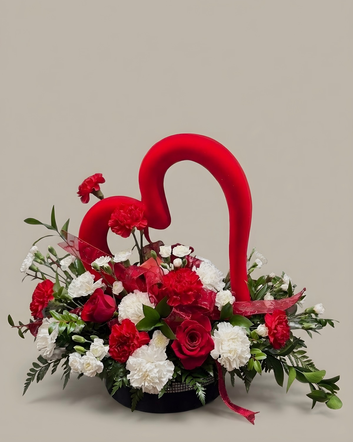 Red and white carnations with a red candy cane and holiday greens