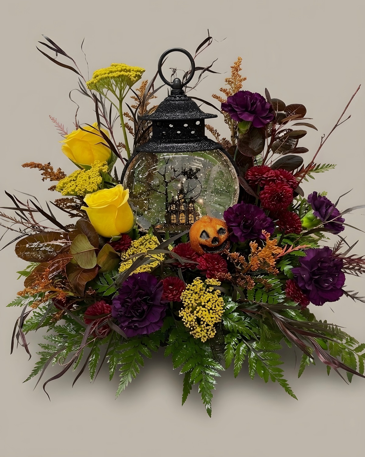 Yellow roses, burgundy carnations and dried grasses around a black lantern